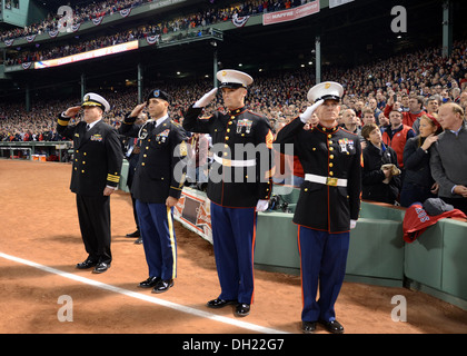 La Cmdr. Sean Kearns, 73rd comandante della USS Constitution, estrema sinistra, saluta il ensign nazionale insieme con i membri del servizio da parte degli Stati Uniti Esercito e Marine Corps durante il canto dell'inno nazionale al gioco 1 della serie Mondiale al Fenway Park. Sa Foto Stock