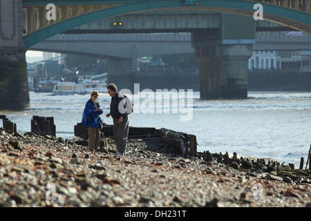 Persone alla ricerca del Tamigi a riva vicino a Southwark Bridge con la bassa marea. Foto Stock