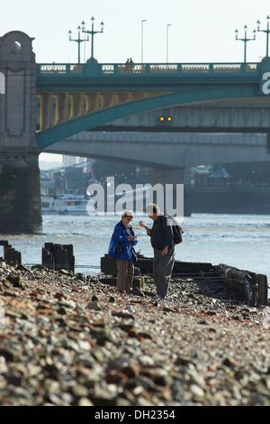 Persone alla ricerca del Tamigi a riva vicino a Southwark Bridge con la bassa marea. Foto Stock