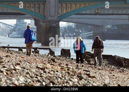 Persone alla ricerca del Tamigi a riva vicino a Southwark Bridge con la bassa marea. Foto Stock