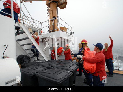 Membri della USCG taglierina Hollyhock equipaggio di operare insieme per la distribuzione di tute di sopravvivenza durante un'esercitazione di abbandono nave, Ottobre 17, 2013.Hollyhock's equipaggio ha eseguito un totale di 55 punte durante il loro transito da quattro mesi di secco periodo di dock a Baltimore, Md. alla loro casa Foto Stock