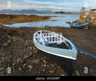 Contea di Galway, Irlanda: imbarcazioni a remi sedersi sul fango appartamenti a bassa marea, Roundstone Harbour Foto Stock