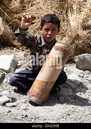 Musulmani indiani i bambini giocando con esercito indiano cartuccia di artiglieria casi vicino al confine pakistano. Turkuk, Ladakh, India Foto Stock