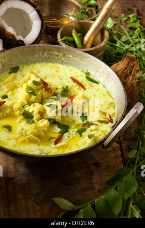 Il cibo Indiano sud indiana curry vegetale con noce di cocco, cavolfiore, patata, curcuma, peperoncino e foglie di curry Foto Stock