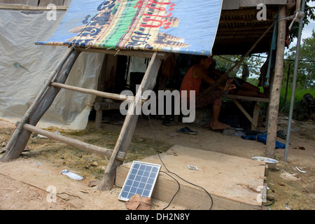 Un piccolo portatile pannello solare fornisce elettricità a case di legno nei pressi di una grande discarica di rifiuti in Phnom Penh Cambogia. Foto Stock