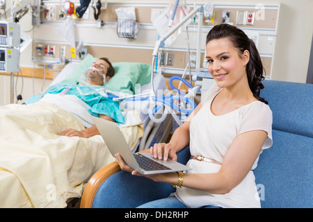 Donna con notebook seduta al paziente di sesso maschile in ospedale Foto Stock