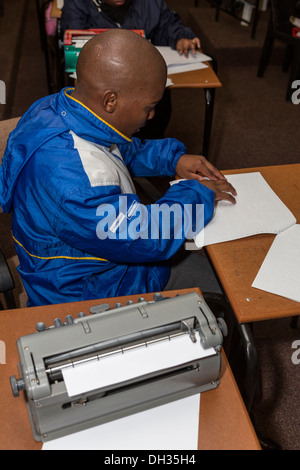 Sud Africa, Cape Town. Studente cieco lettura Braille. Un motore Perkins Brailler stampante è in primo piano. Foto Stock