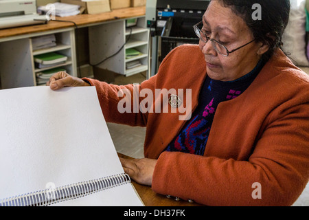 Sud Africa, Cape Town. Editor Braille esaminando le cartelle di lavoro stampate per gli studenti. Athlone scuola per ciechi. Foto Stock