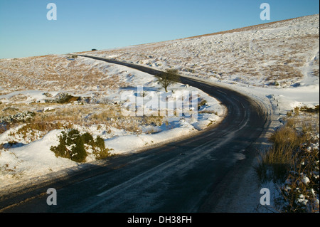 La strada si snoda attraverso snowbound brughiera, vicino Postbridge, Parco Nazionale di Dartmoor, Devon, Gran Bretagna. Foto Stock