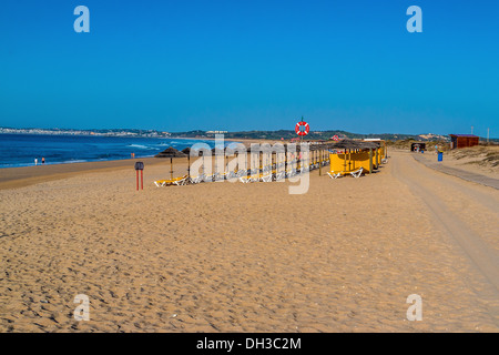 Sedie a sdraio e ombrelloni in una spiaggia deserta Foto Stock