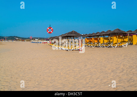 Sedie a sdraio e ombrelloni in una spiaggia deserta Foto Stock