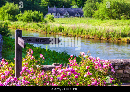 Fila di tessitori' cottages, Arlington Row, a Bibury, Gloucestershire visto attraverso il Fiume Coln e il Rack Isle prato d'acqua. Foto Stock