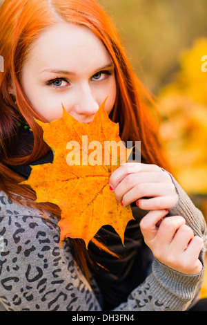 Sorridente i Capelli rossi ragazza e foglie di acero, close-up Foto Stock