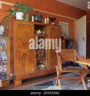 Sedia in legno al tavolo di fronte a deco e armadio con apertura centrale ripiani in rosso la sala da pranzo Foto Stock