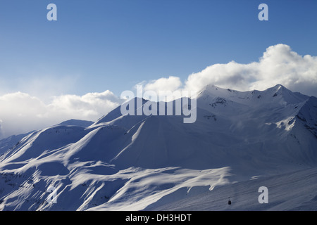 Vista sulla pista da sci e sole montagne in serata. Stazione sciistica Gudauri. Montagne del Caucaso, Georgia. Foto Stock