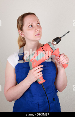 Giovane donna su un sito di costruzione in possesso di una macchina perforatrice nelle sue mani Foto Stock