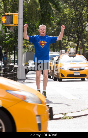 Vittorioso uomo Senior Jogging sulle strade della città indossando Superman T-Shirt, NYC Foto Stock