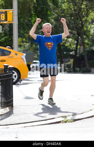 Vittorioso uomo Senior Jogging sulle strade della città indossando Superman T-Shirt, NYC Foto Stock