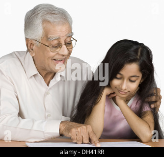 Senior uomo la lettura di un libro con la sua nipote Foto Stock