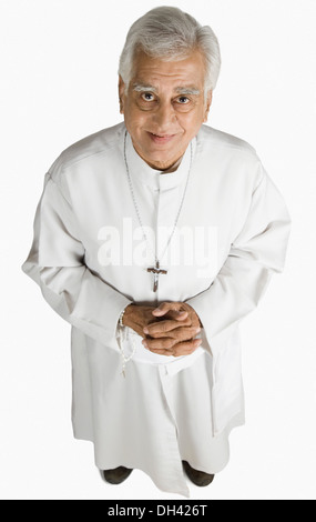 Ritratto di un sacerdote in piedi con le mani incrociate e sorridente Foto Stock