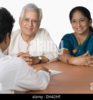 Paio di discutere con un consulente finanziario e sorridente Foto Stock