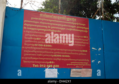 Un segno di assunzione che delinea i salari e benefici è posto all'ingresso di una fabbrica di indumento in Phnom Penh Cambogia. Foto Stock