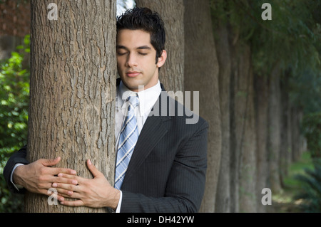 Imprenditore abbracciando un albero Foto Stock