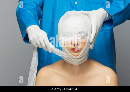Chirurgo bendaggio di incarto sul volto di donna Foto Stock