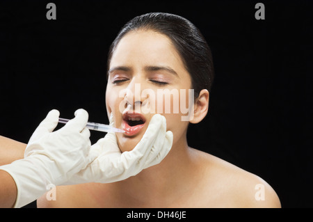 Al chirurgo la mano di iniettare sulla donna di labbro Foto Stock