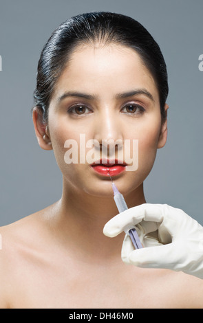 Al chirurgo la mano di iniettare sulla donna di labbro Foto Stock