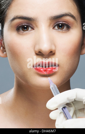 Al chirurgo la mano di iniettare sulla donna di labbro Foto Stock