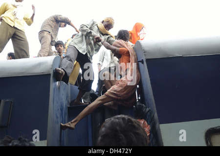 Uomo indiano tirando verso l'alto e la donna cercando di salire sul tetto del vagone ferroviario compartimento di treno Jodhpur Rajasthan India Asia Foto Stock