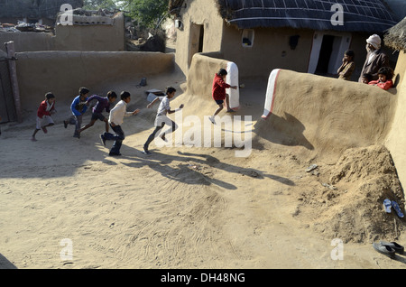 Rurale indiano boys in esecuzione per la loro casa nei pressi di Bikaner Rajasthan in India Foto Stock