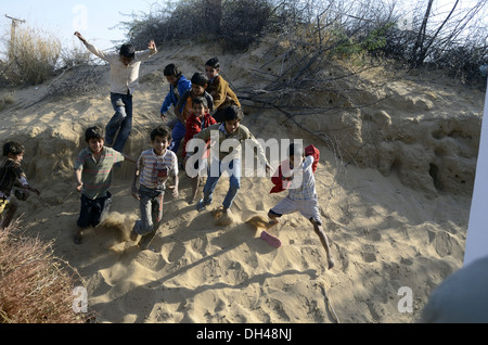 Ragazzi giocare in esecuzione sul deserto di sabbia vicino a Bikaner Rajasthan in India Foto Stock