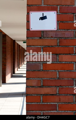 Segno con una telecamera il pittogramma di avvertimento di video-sorveglianza su un rosso un muro di mattoni. Foto Stock