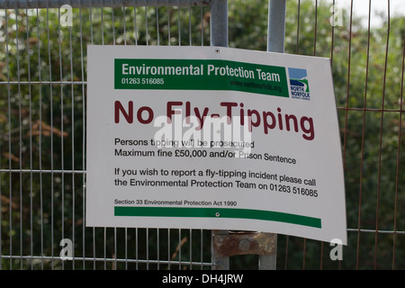 Segnale; lettura Fly-Tipping n. North Norfolk consiglio del distretto. Attaccata alla recinzione di sicurezza intorno a un campo marrone sito. Foto Stock