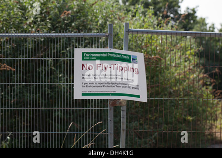 Segnale; lettura Fly-Tipping n. North Norfolk consiglio del distretto. Attaccata alla recinzione di sicurezza intorno a un campo marrone sito. Foto Stock