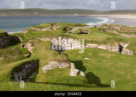 Isole di Orkney, Scozia. L'insediamento neolitico a Skara Brae, con la baia di Skaill in background. Foto Stock