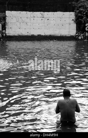 Muro Bianco e uomo che prega in Banganga Serbatoio acqua Walkeshwar Mumbai India Maharashtra 2012 Foto Stock