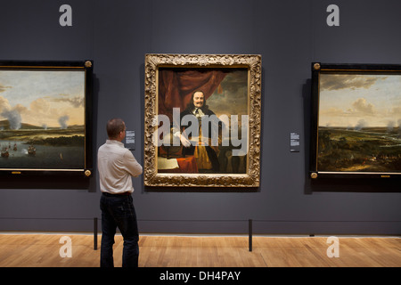 Paesi Bassi, Amsterdam, Rijksmuseum. Visitatore guardando alla pittura di Michiel de Ruyter come tenente - Admiral, Ferdinand Bol Foto Stock