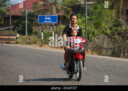 Ritratto orizzontale di un padre e figlio su un ciclomotore insieme al sole. Foto Stock