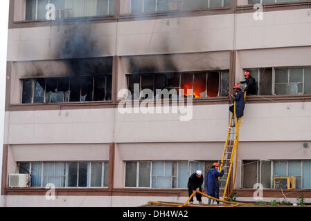 Vigili del fuoco impegnati a spegnere un incendio a combustione edificio dopo gli incendi scoppiati incidenti dovuti a elettrico corto-circuito al fondo benevola edificio nella città di Peshawar giovedì 31 ottobre, 2013. Foto Stock