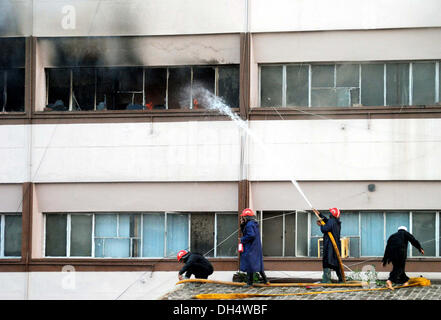 Vigili del fuoco impegnati a spegnere un incendio a combustione edificio dopo gli incendi scoppiati incidenti dovuti a elettrico corto-circuito al fondo benevola edificio nella città di Peshawar giovedì 31 ottobre, 2013. Foto Stock