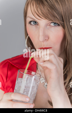 Glas con cubetti di ghiaccio e il liquido trasparente drink in mano di una giovane donna Foto Stock