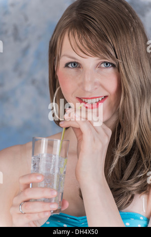 Glas con cubetti di ghiaccio e il liquido trasparente drink in mano di una giovane donna Foto Stock