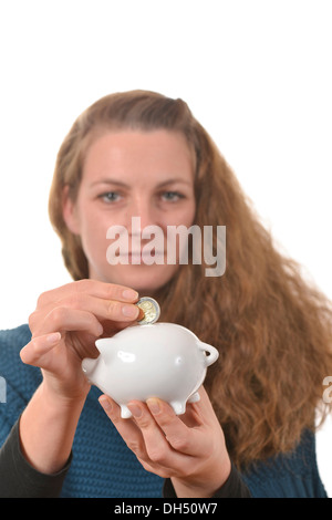 Donna mettendo a 2 euro monete in un salvadanaio Foto Stock