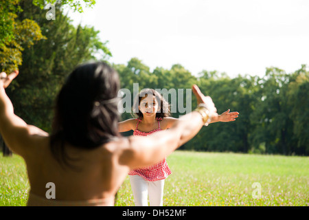 Ragazza che corre verso la madre con le braccia tese Foto Stock