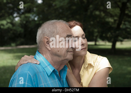 Donna che abbraccia un uomo anziano, con gli occhi chiusi Foto Stock