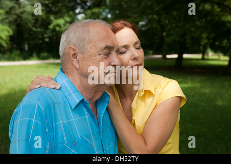 Donna che abbraccia un uomo anziano, con gli occhi chiusi Foto Stock