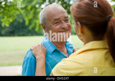 Donna che abbraccia un uomo anziano Foto Stock